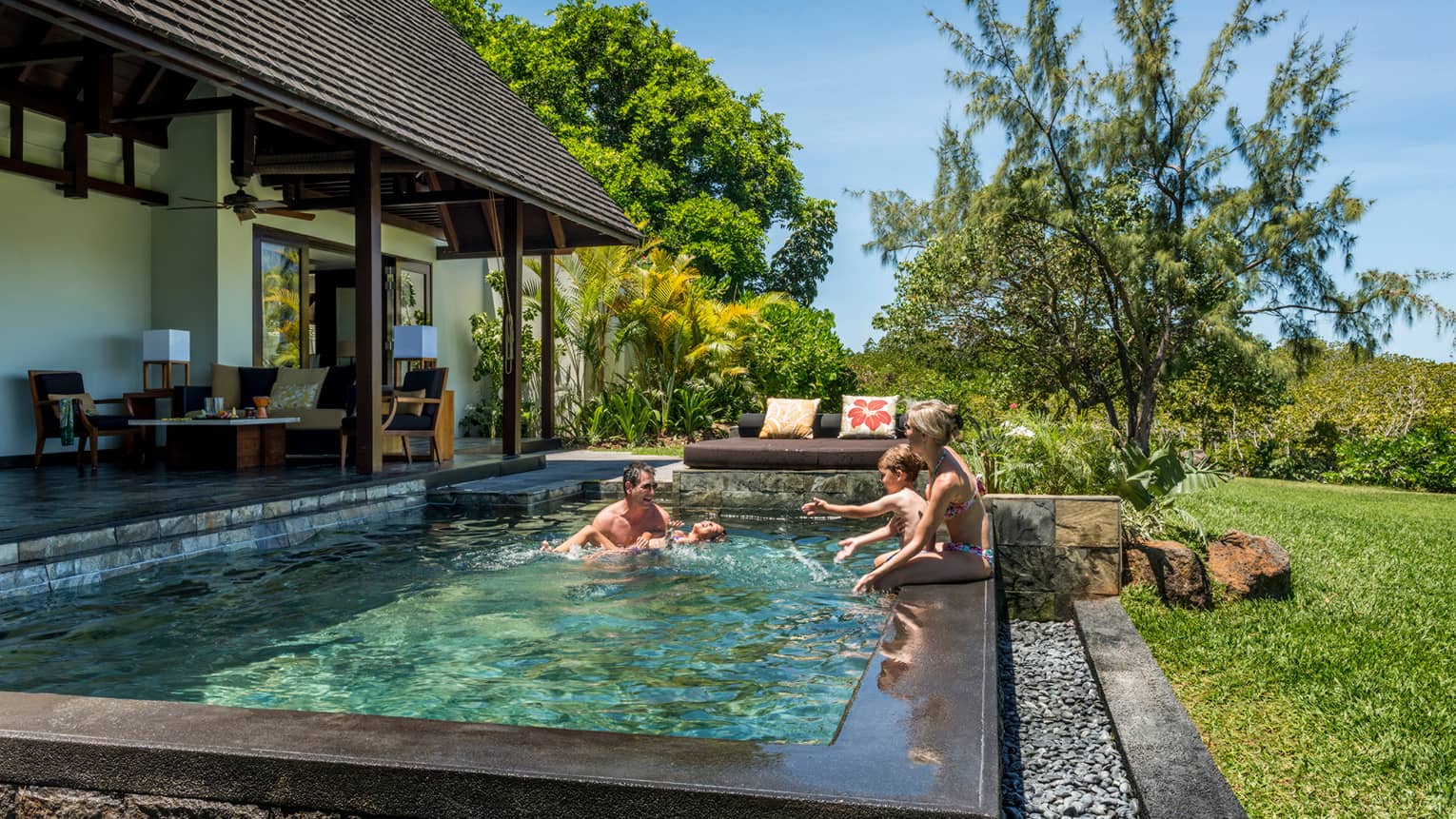 Couple, two children laugh, splash in sunny Garden Villa plunge swimming pool