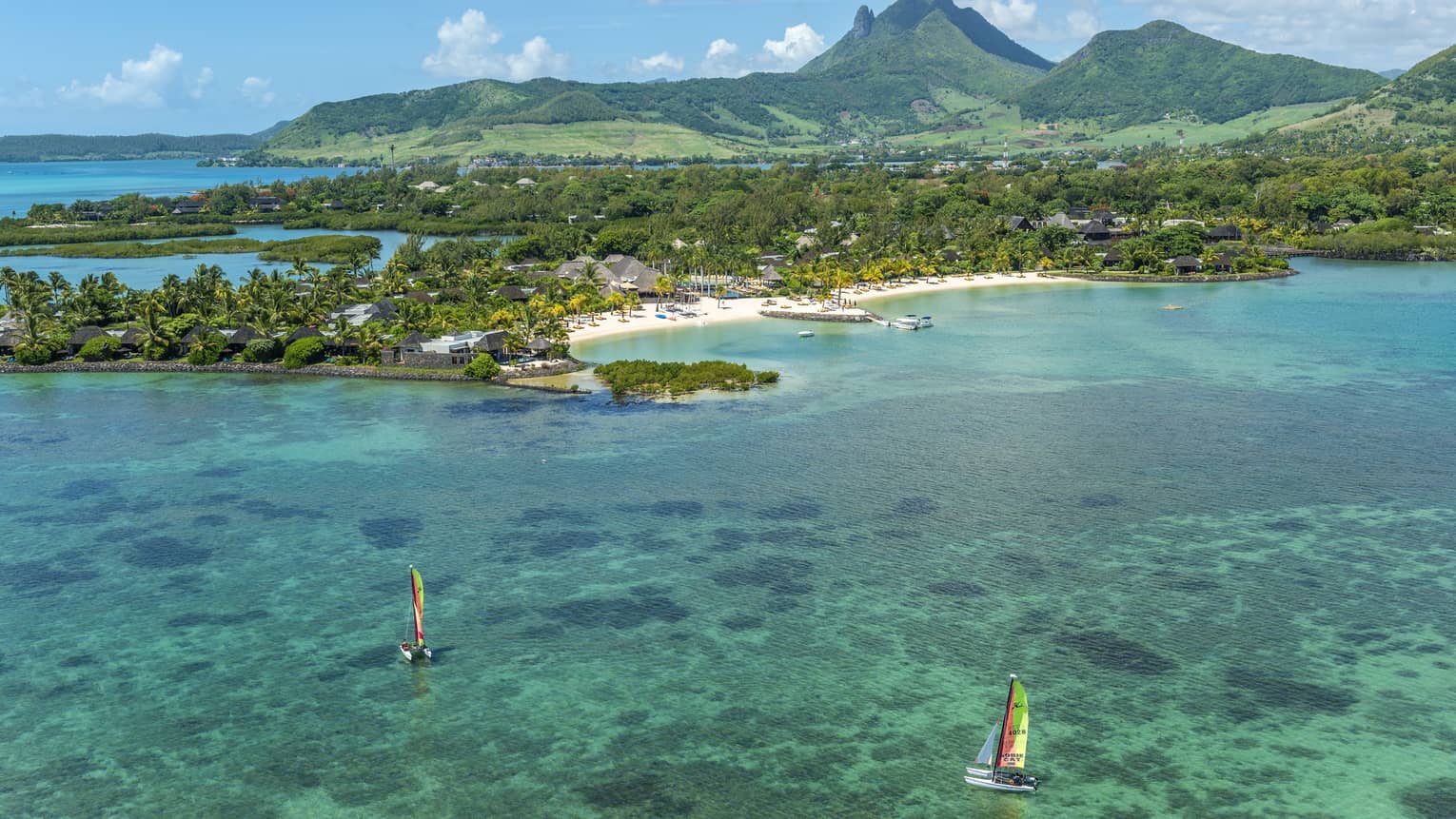 Aerial view of two colourful sailboats on turquoise water in lagoon