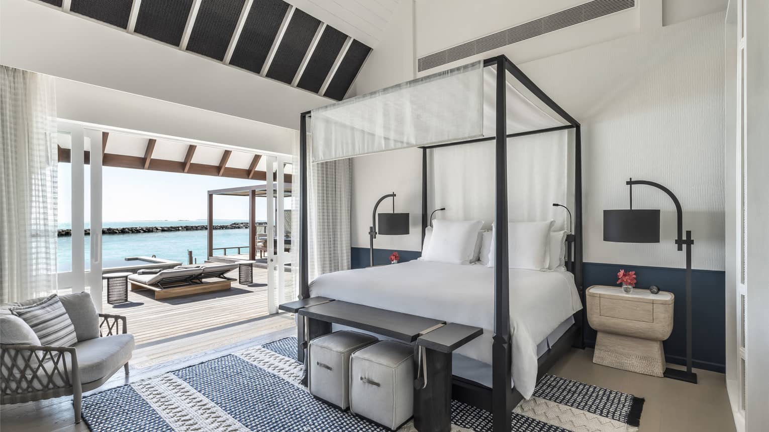Bedroom with four-poster canopied bed with doorway leading to pool deck with cabana