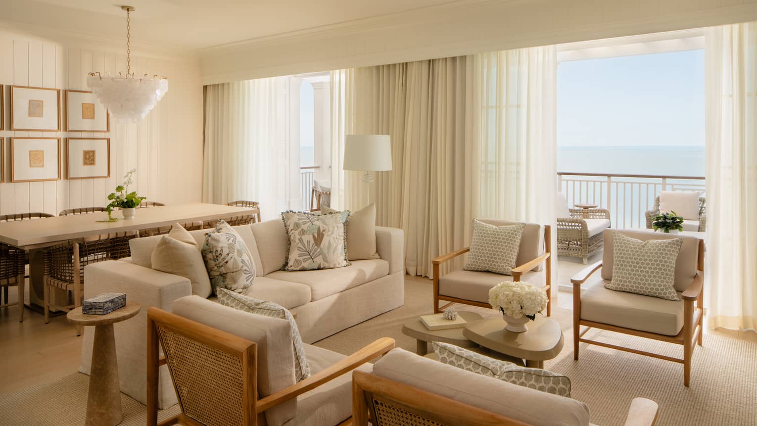 Luxury resort suite featuring a light-filled living room with off-white seating and a dining area