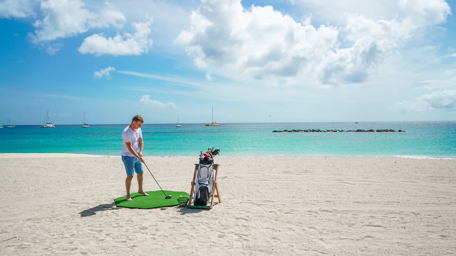 A man golfing on a clean beach near the ocean.