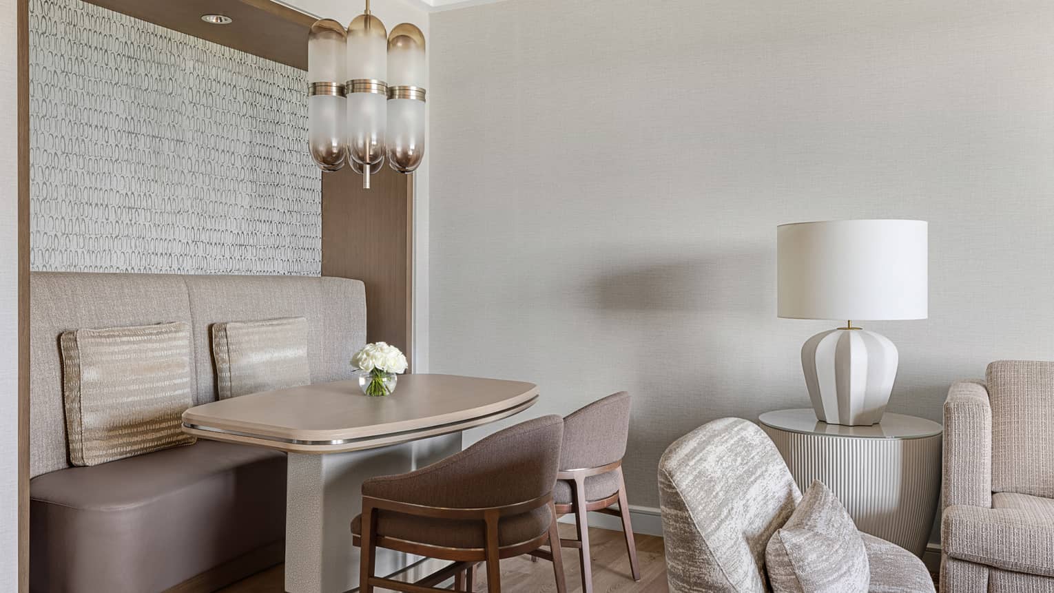 Dining table four four, with wall booth seating and two chairs, in a neutral-coloured living room