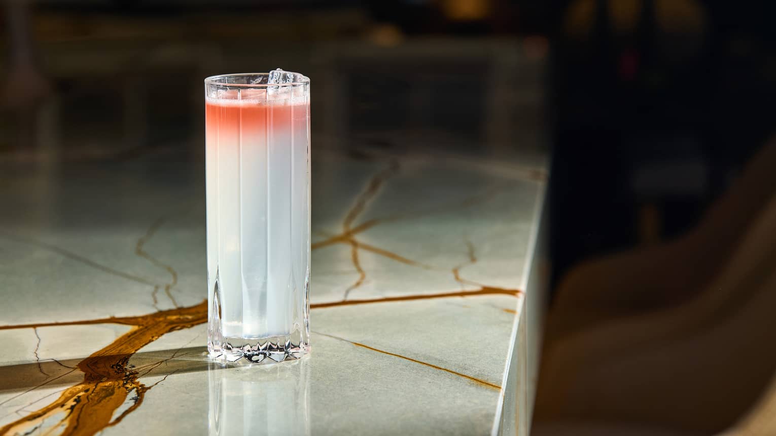 Light-coloured cocktail placed in a sunbeam on a marble counter