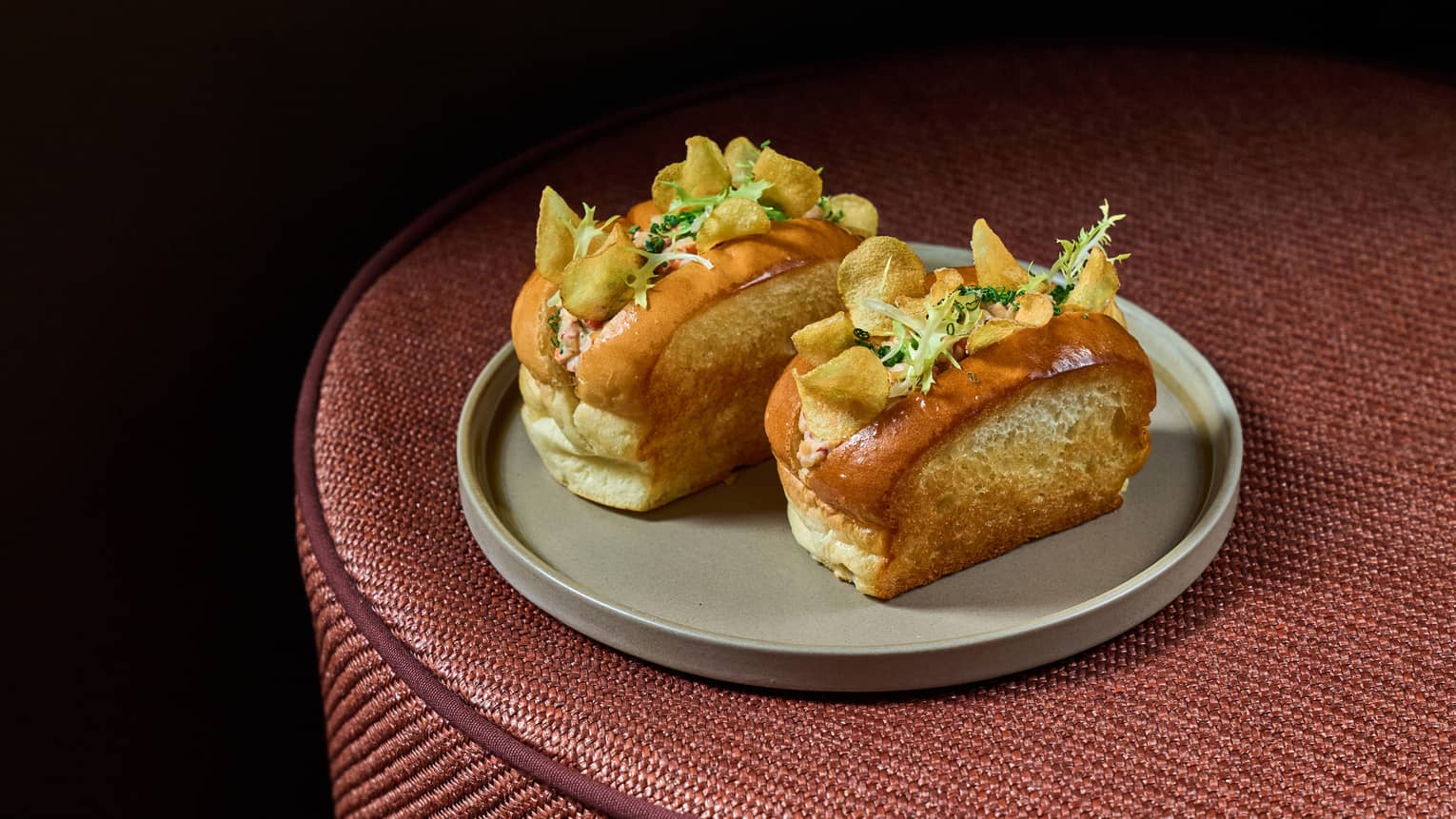 Two lobster rolls topped with potato chips