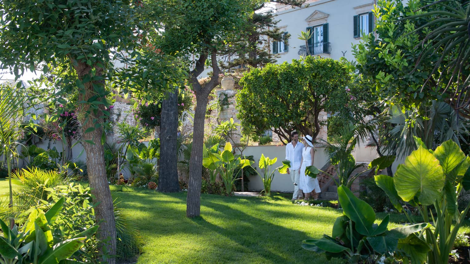 Couple dressed in white walking through garden