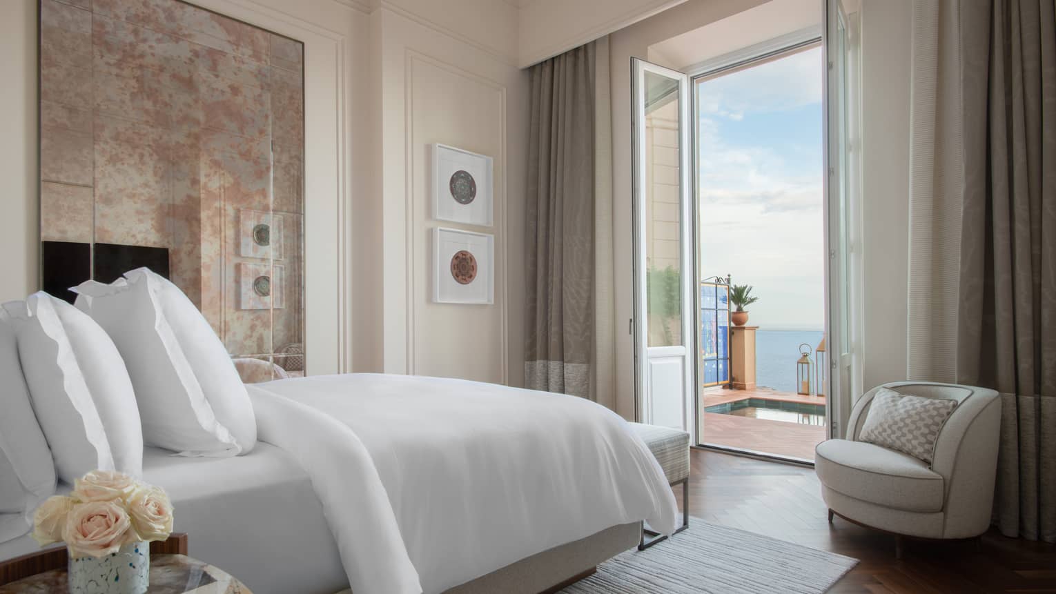 Bedroom with bed facing opened doors to sea-view terrace with plunge pool