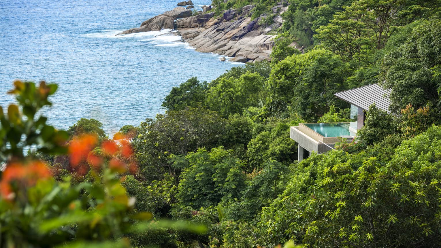 Overview of Villa nested among greenery, ocean and rocky shore below