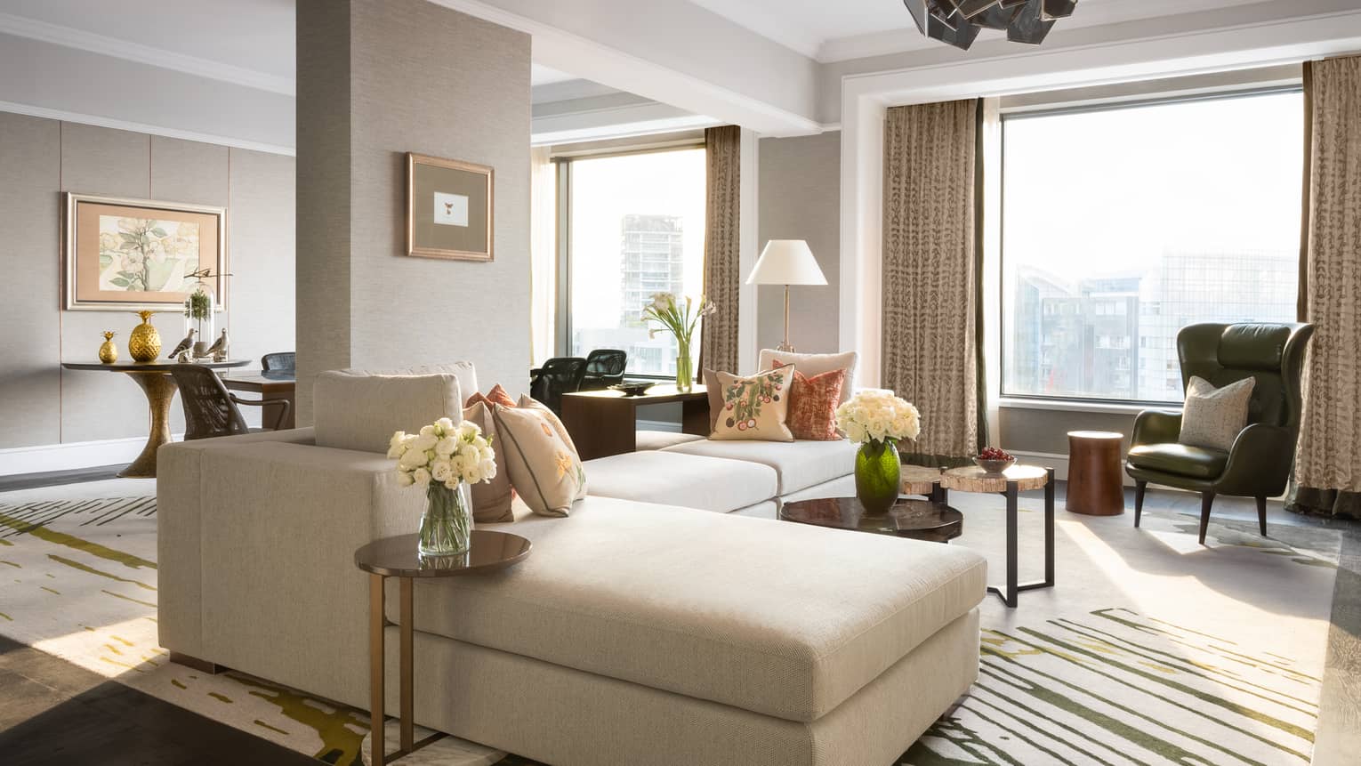 Living area of Royal Suite with cream couch, pillows, white flowers, decor 