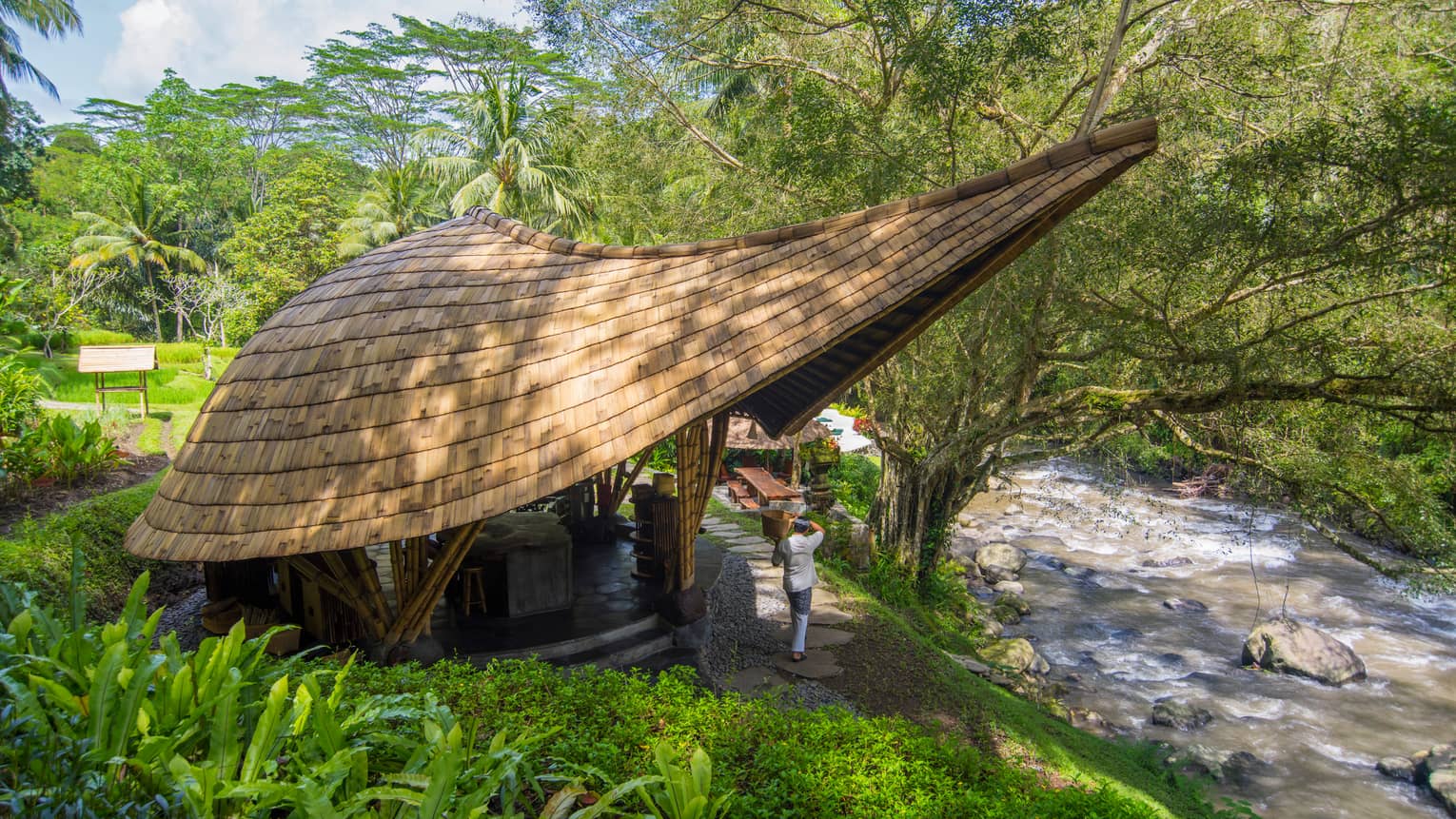 Small building with modern, extended roof overhang, next to river in Bali