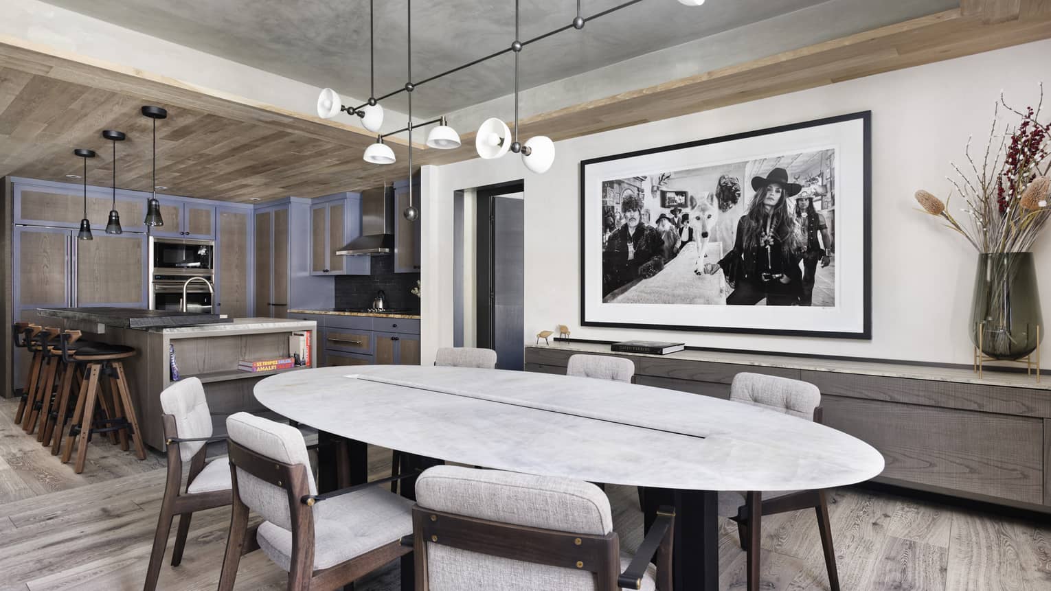 Oval, white marble dining table with six chairs, large photo on wall