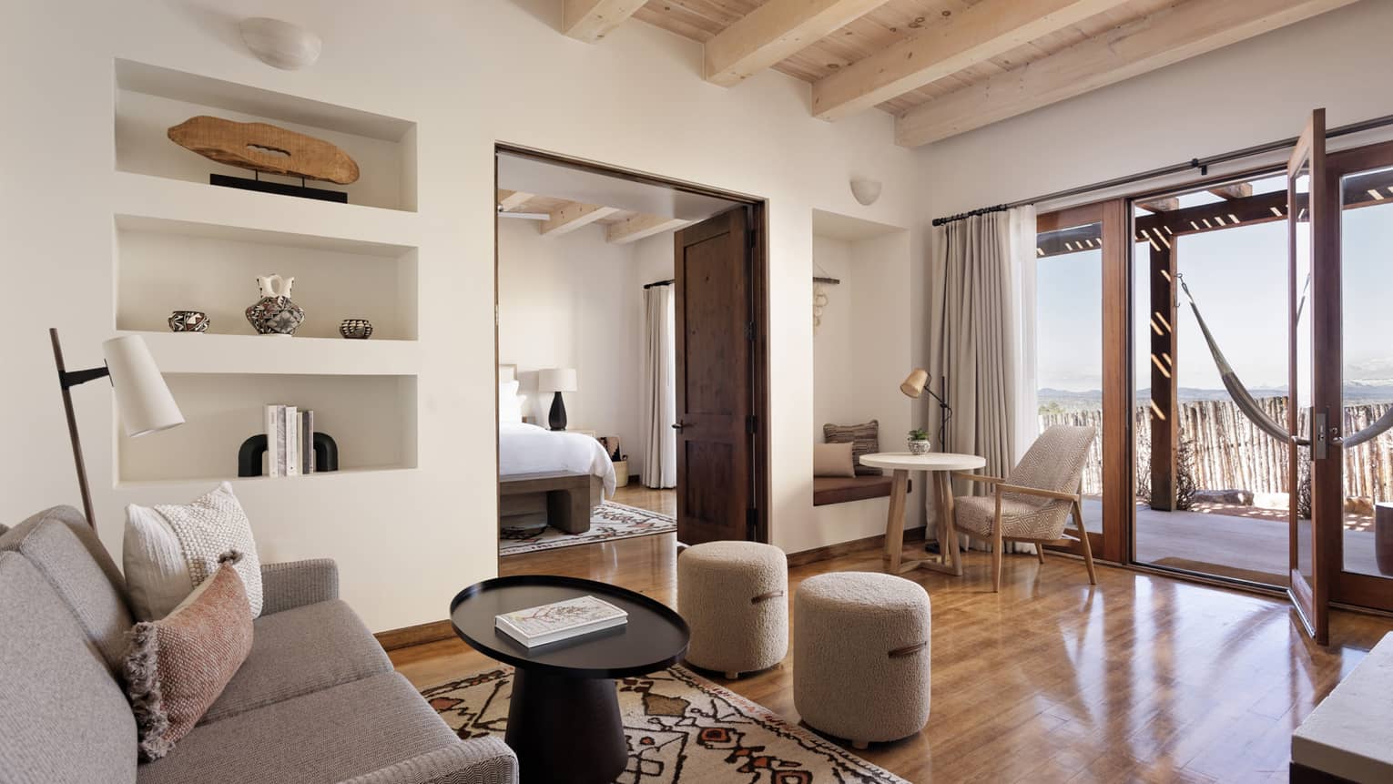 A living room in a suite with a couch and coffee table, and hammock on the patio