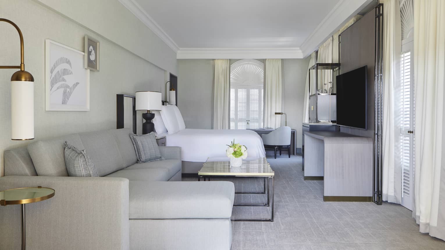 Hotel room with king bed and living area, complete with a grey l-shaped sofa