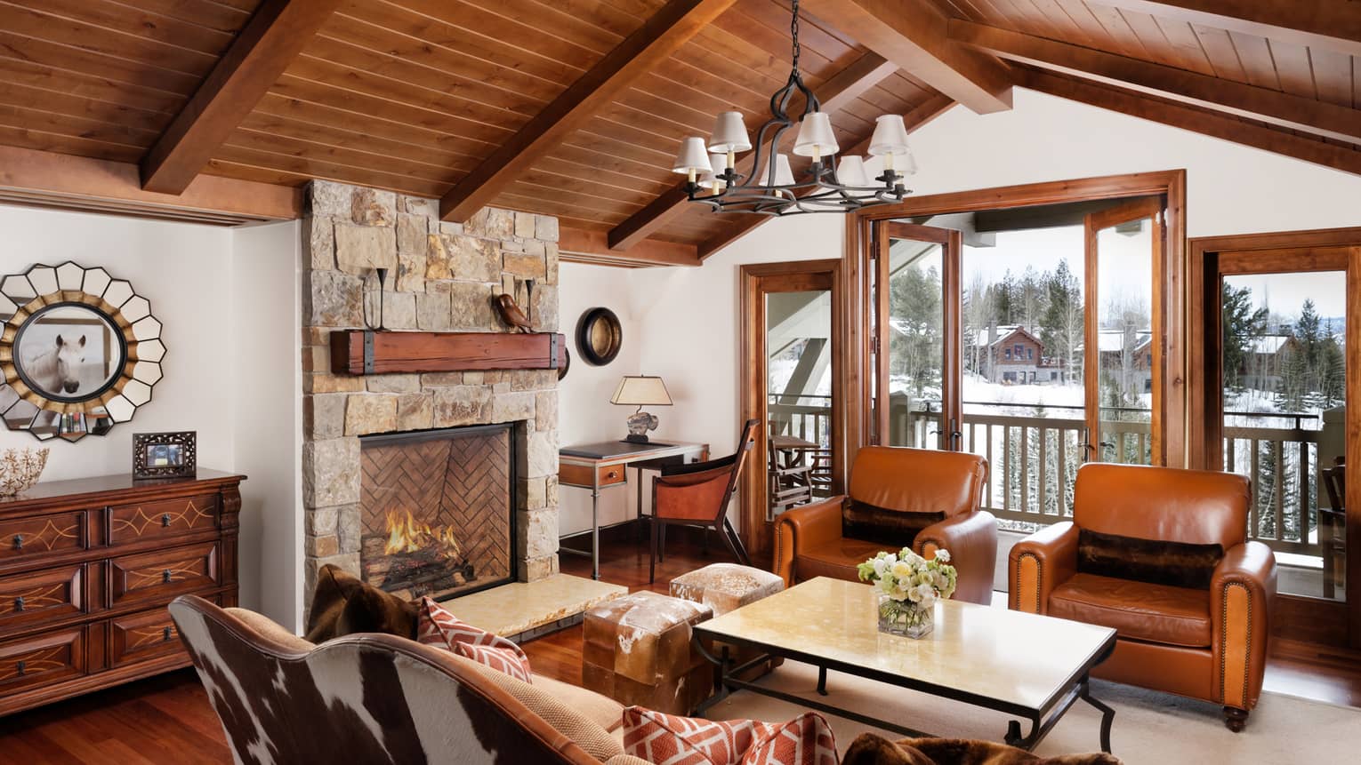 Cowhide sofa, leather armchairs. stone fireplace under arched wood beam ceiling