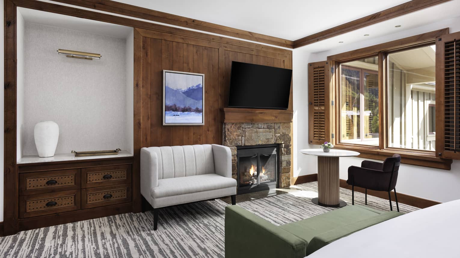 Hotel room with wooden wall, fireplace, love seat, green chaise