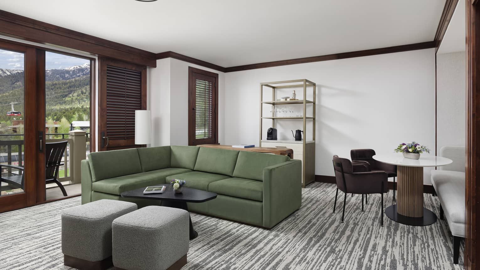 Living room with green sofa, table with two chairs and balcony