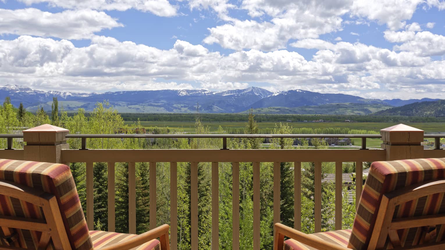 Two chairs on outdoor wooden deck looking out to lush mountain valley