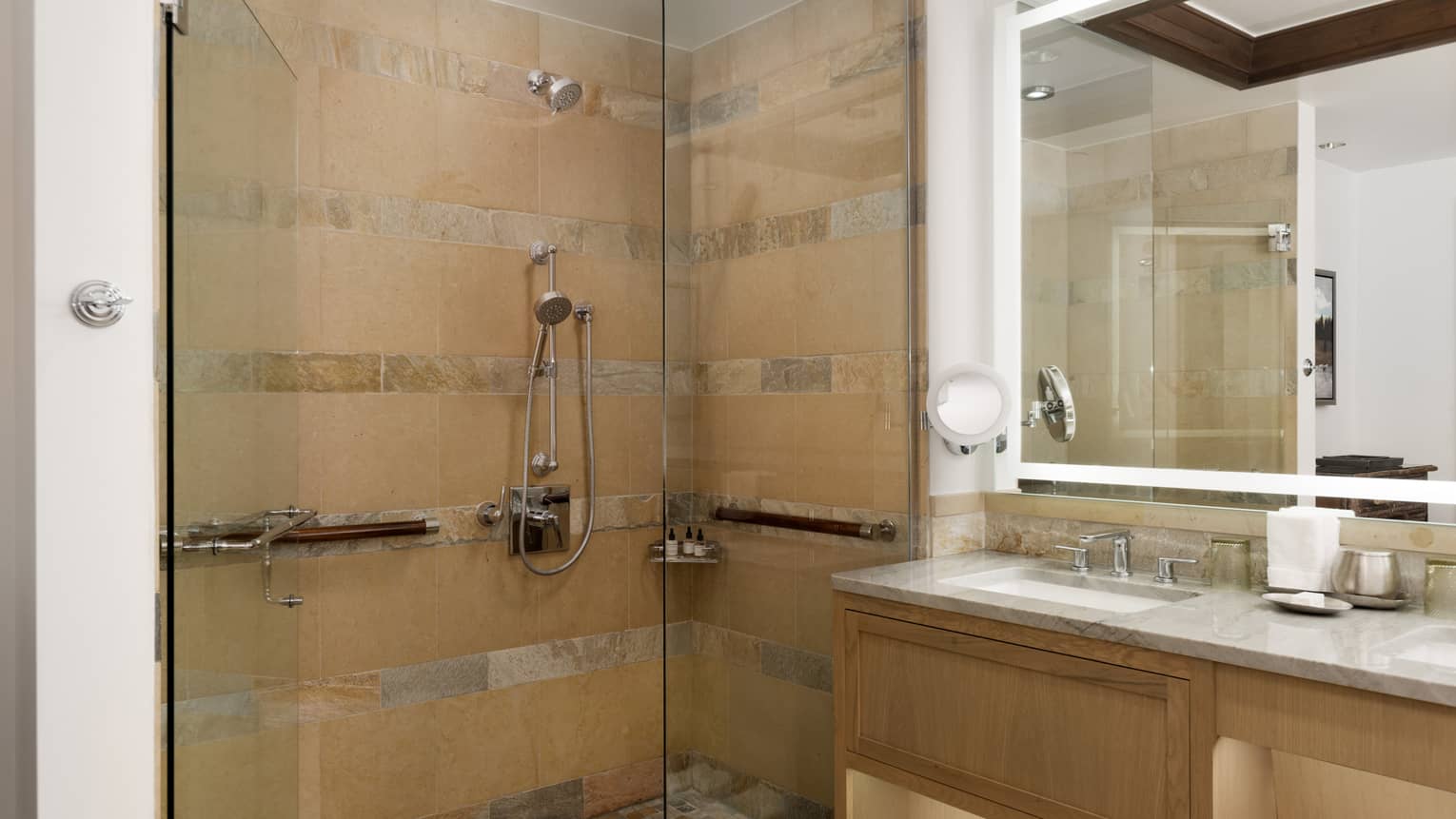 Luxury bathroom with a glass-enclosed shower with beige stone tiles and a backlit vanity mirror