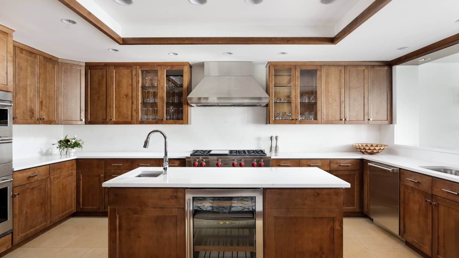 Kitchen with dark wood cupboards and white countertops, island with built-in wine fridge and sink