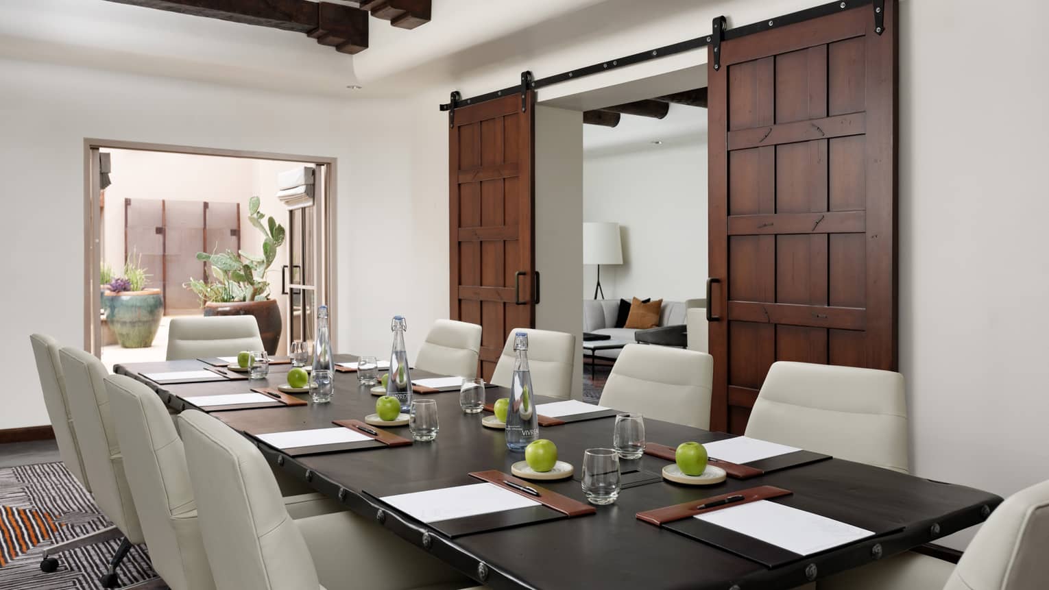 A meeting rom with leather chairs around a large rectangular table, two large wooden sliding door are on a wall.
