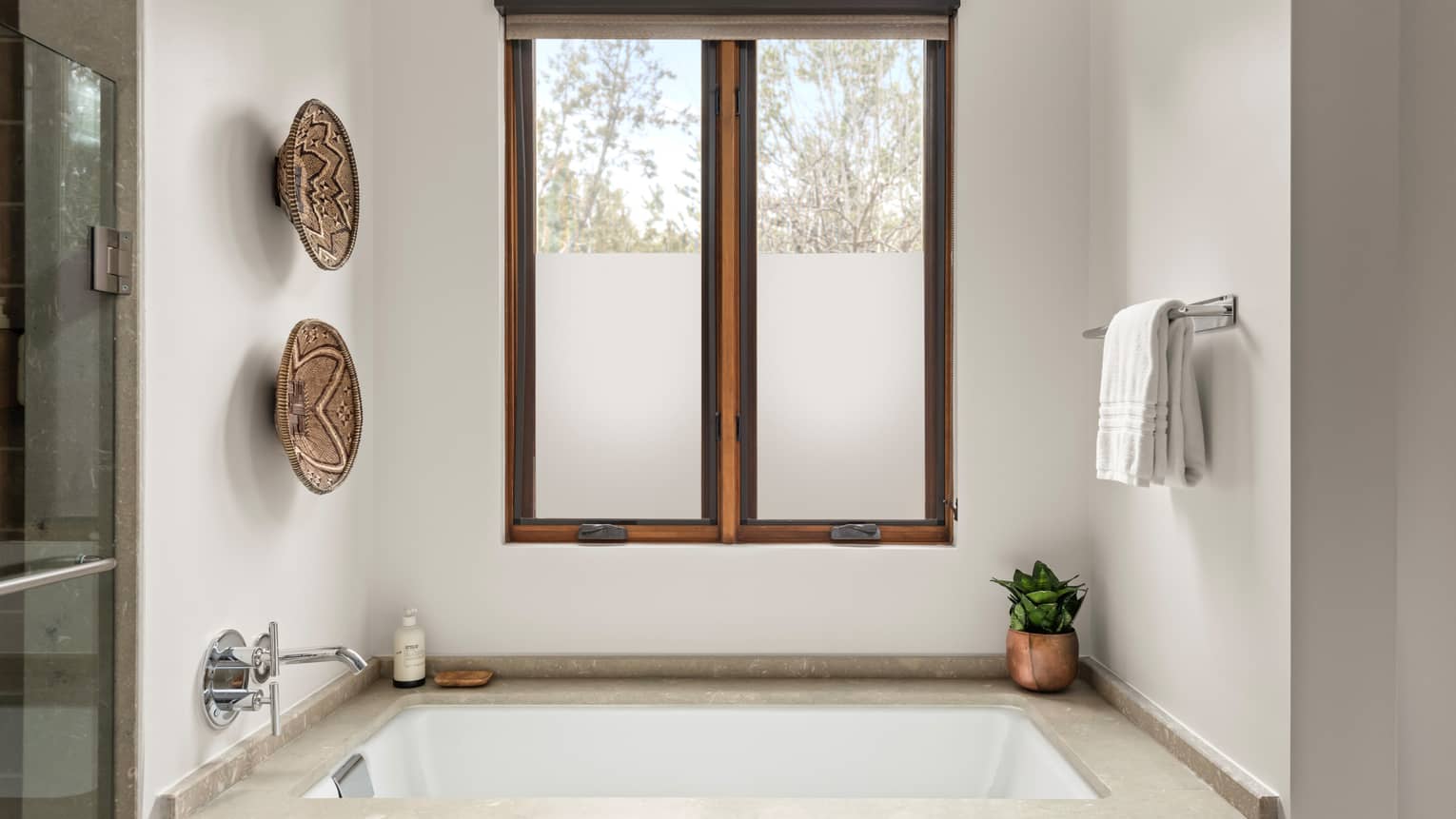 Sunken bathtub next to frosted window in a luxury hotel bathroom at Four Seasons Resort Santa Fe