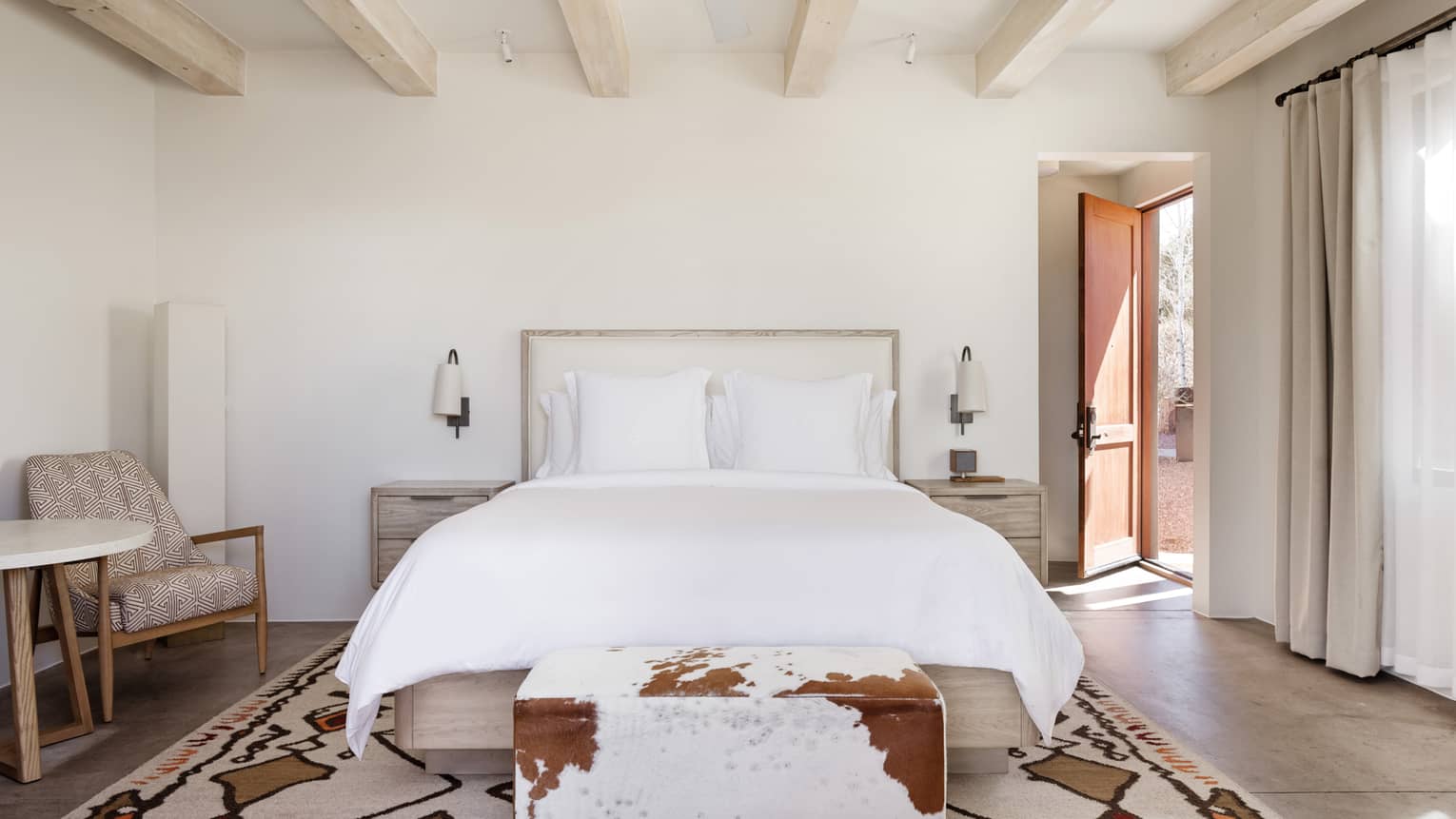 Hotel room with king bed, cowhide bench and beamed ceiling at Four Seasons Resort Santa Fe