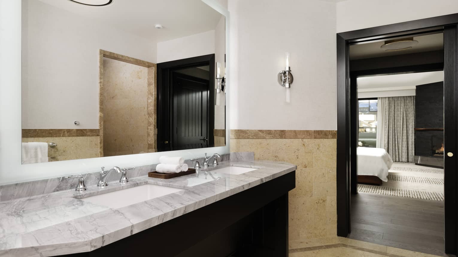 Bathroom with marble double vanity, beige limestone floors and walls