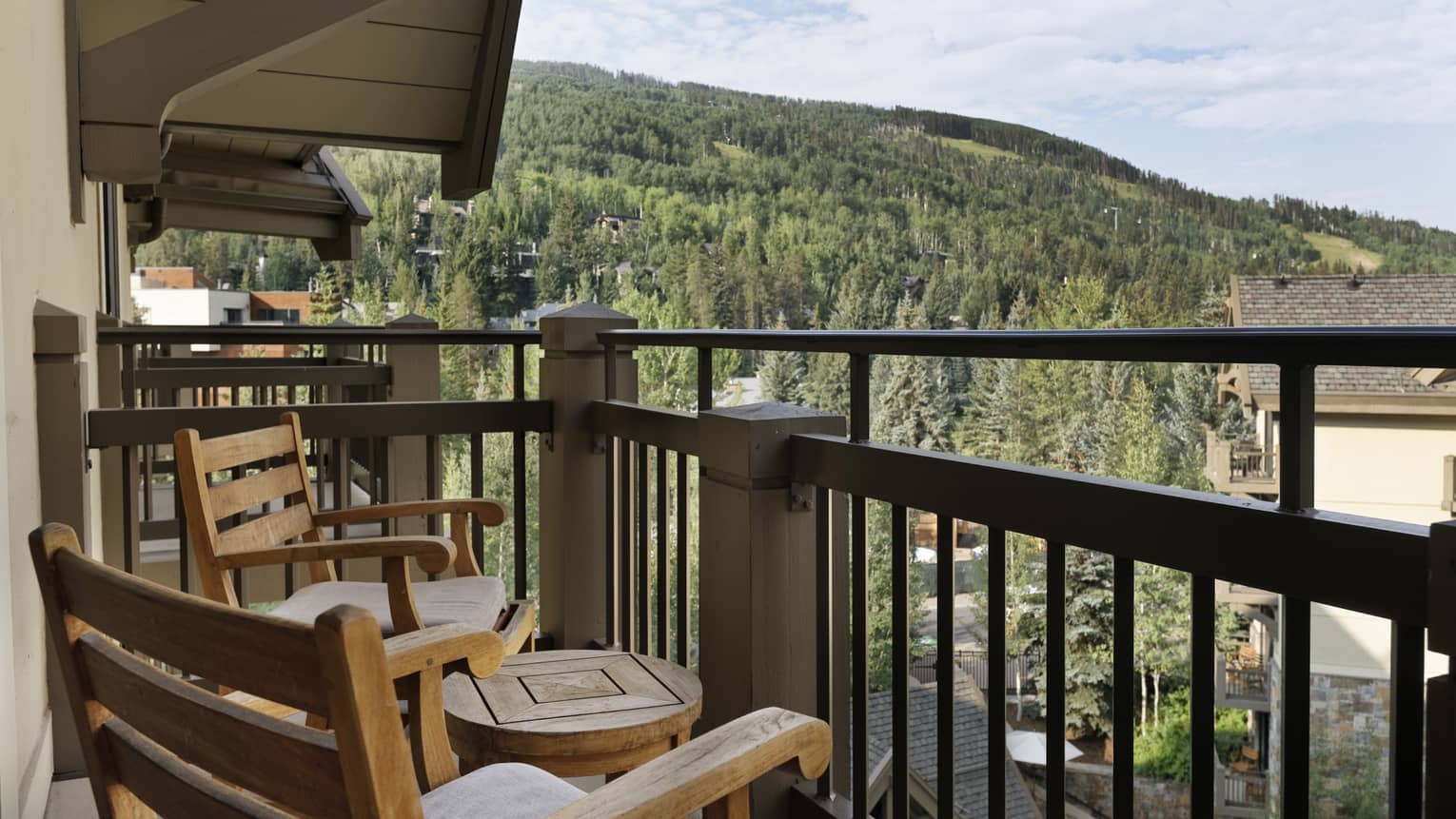 Balcony with portico, two wooden rocking chairs and small round table, mountain views