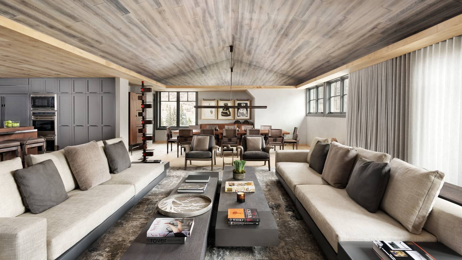 Long beige sofas, two slate coffee tables under wood ceiling