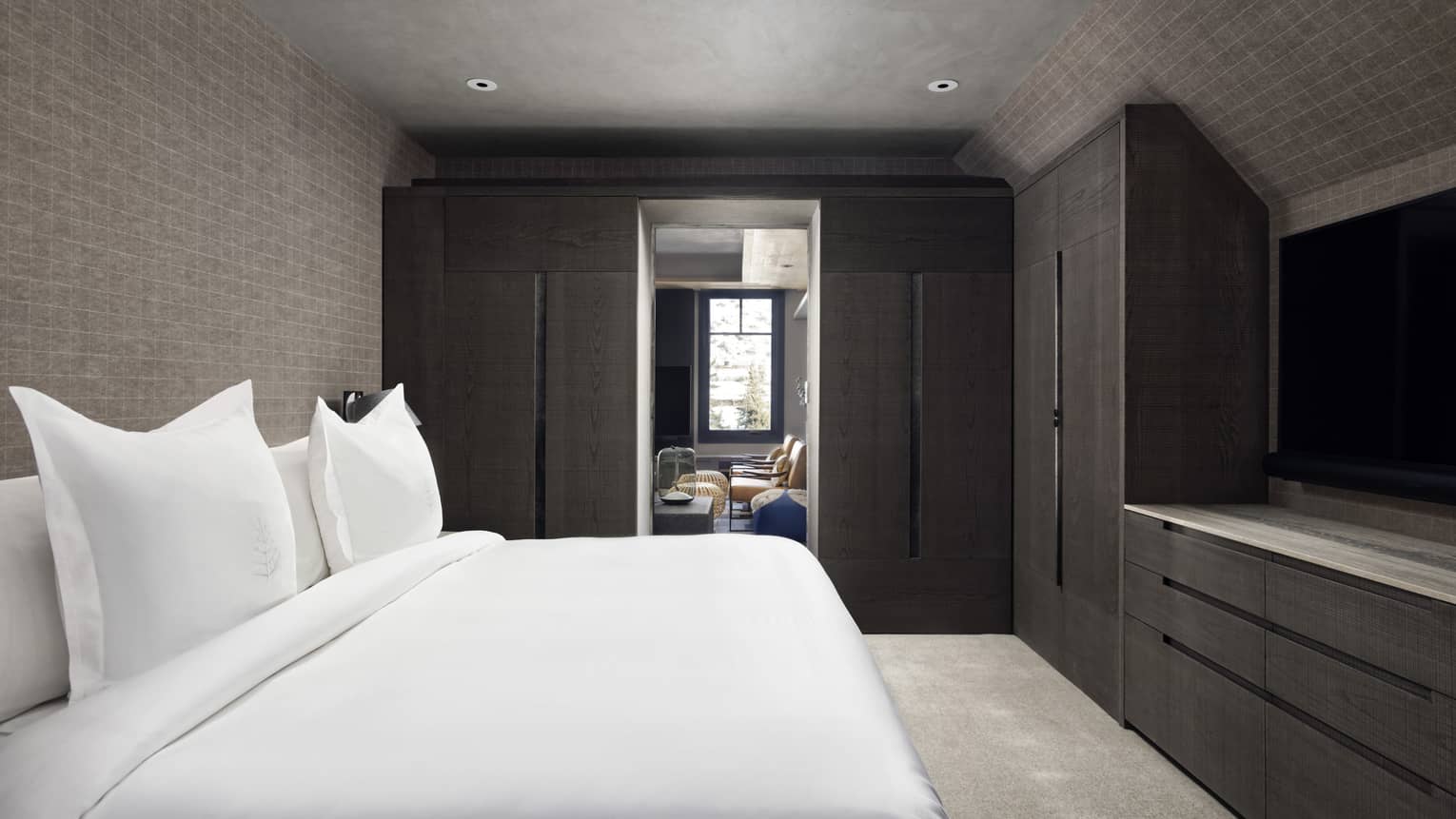 Bedroom with white king bed, built-in wooden wardrobes and dresser