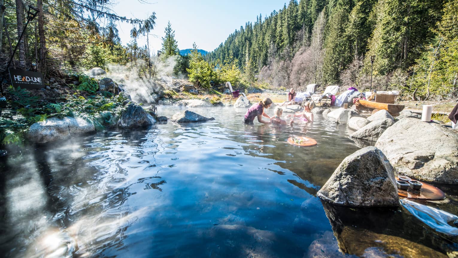Group relaxes in hot springs, surrounded by forest 