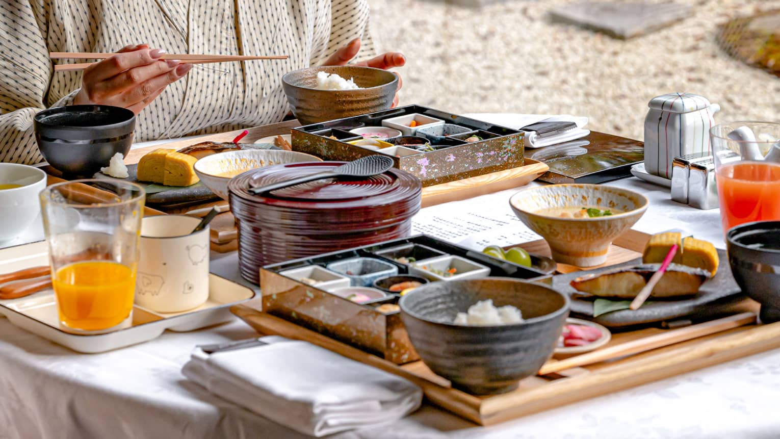 Woman eats breakfast in luxury hotel looking out window to garden