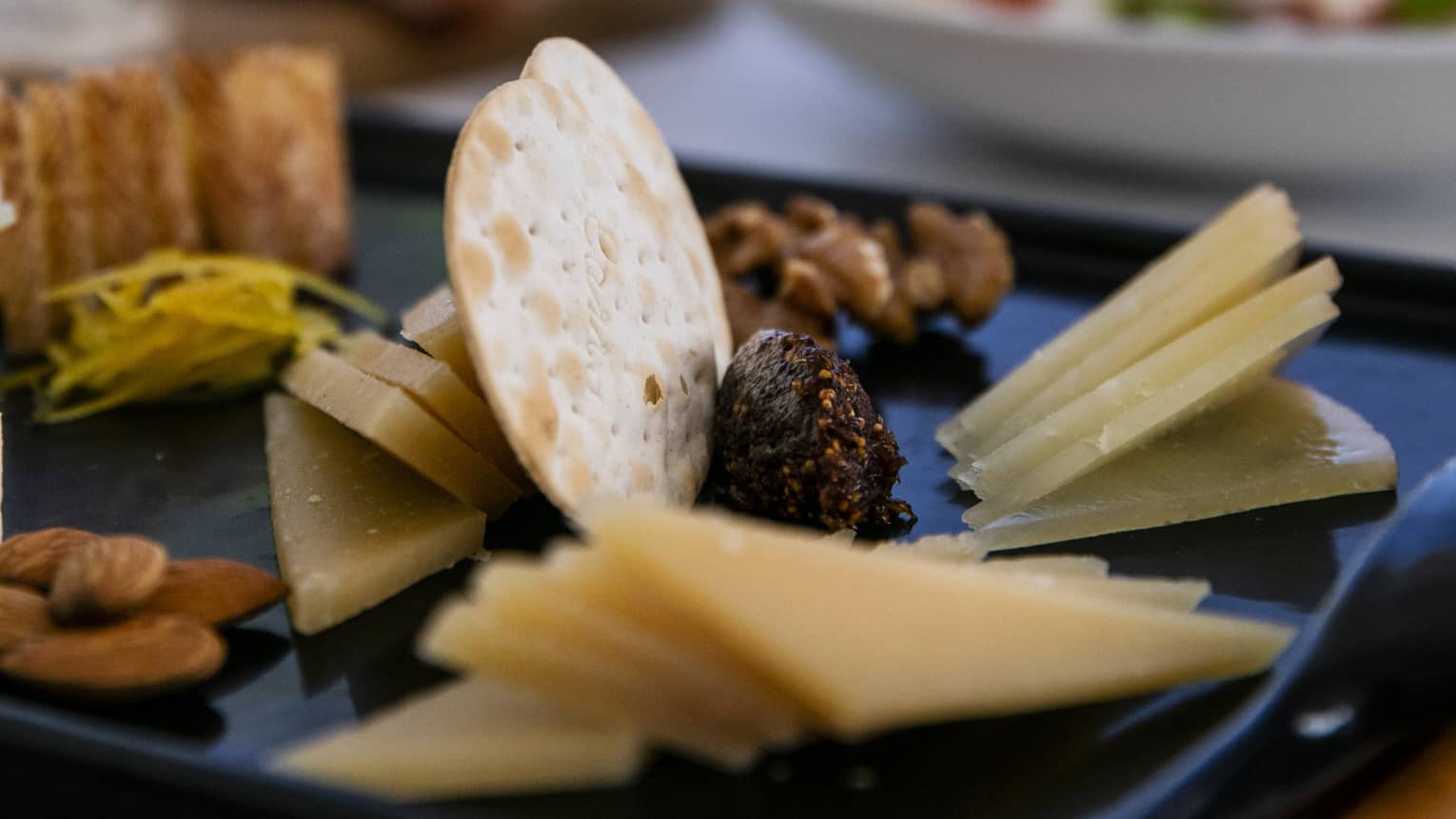 A charteurtie board with cheese, crackers, almonds and raisins