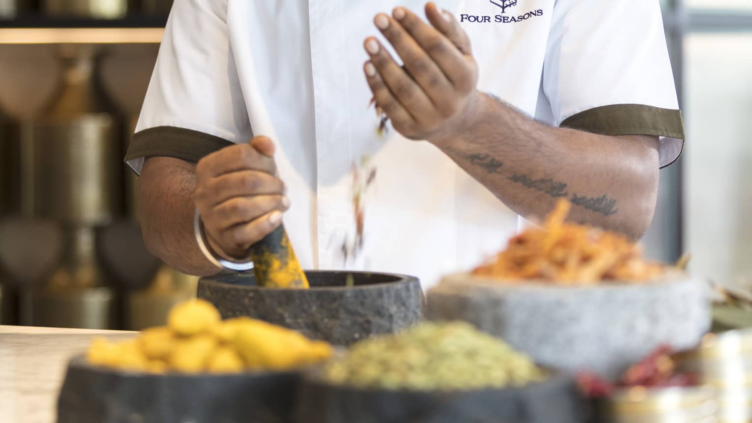 A chef uses a pestle and mortar to grind fresh herbs