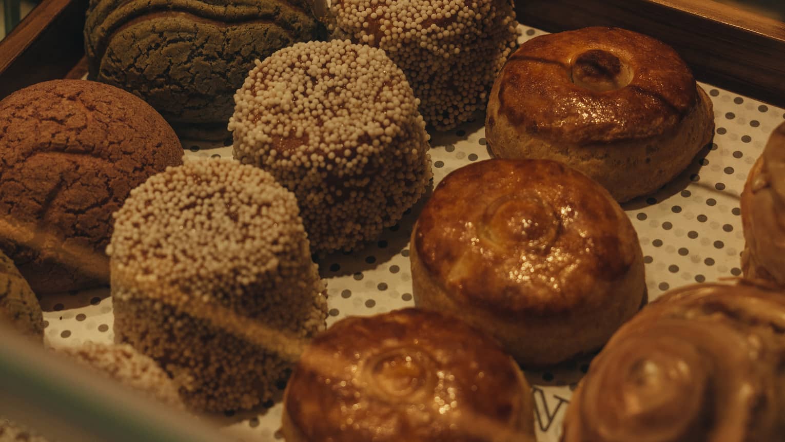 Hand holding silver tongs reaches into a pastry case to grab a small, round cake