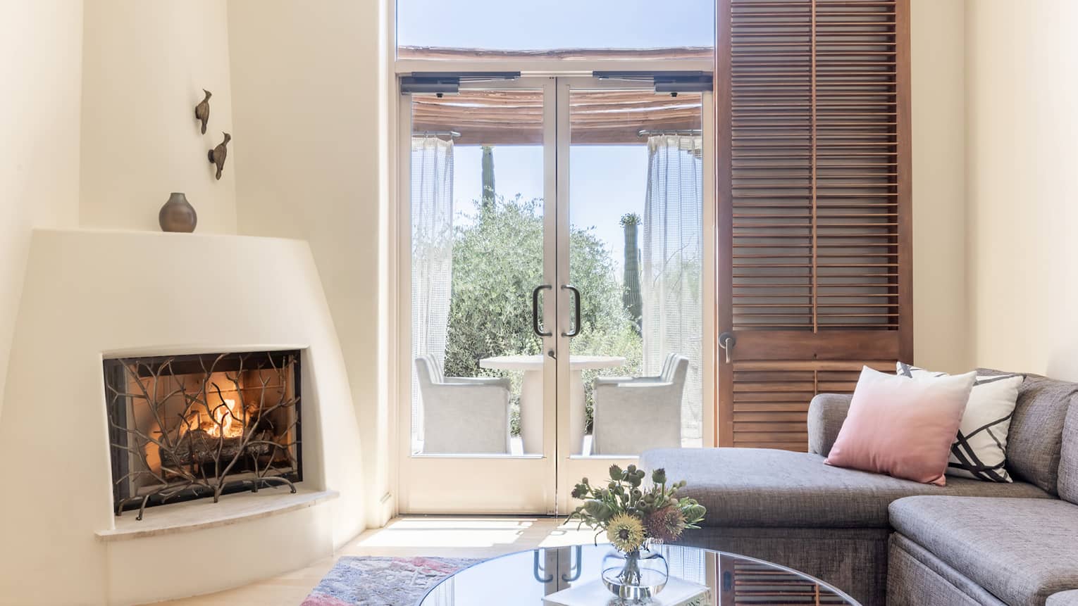 A room with large glass doors, fireplace, a sofa and coffee table.