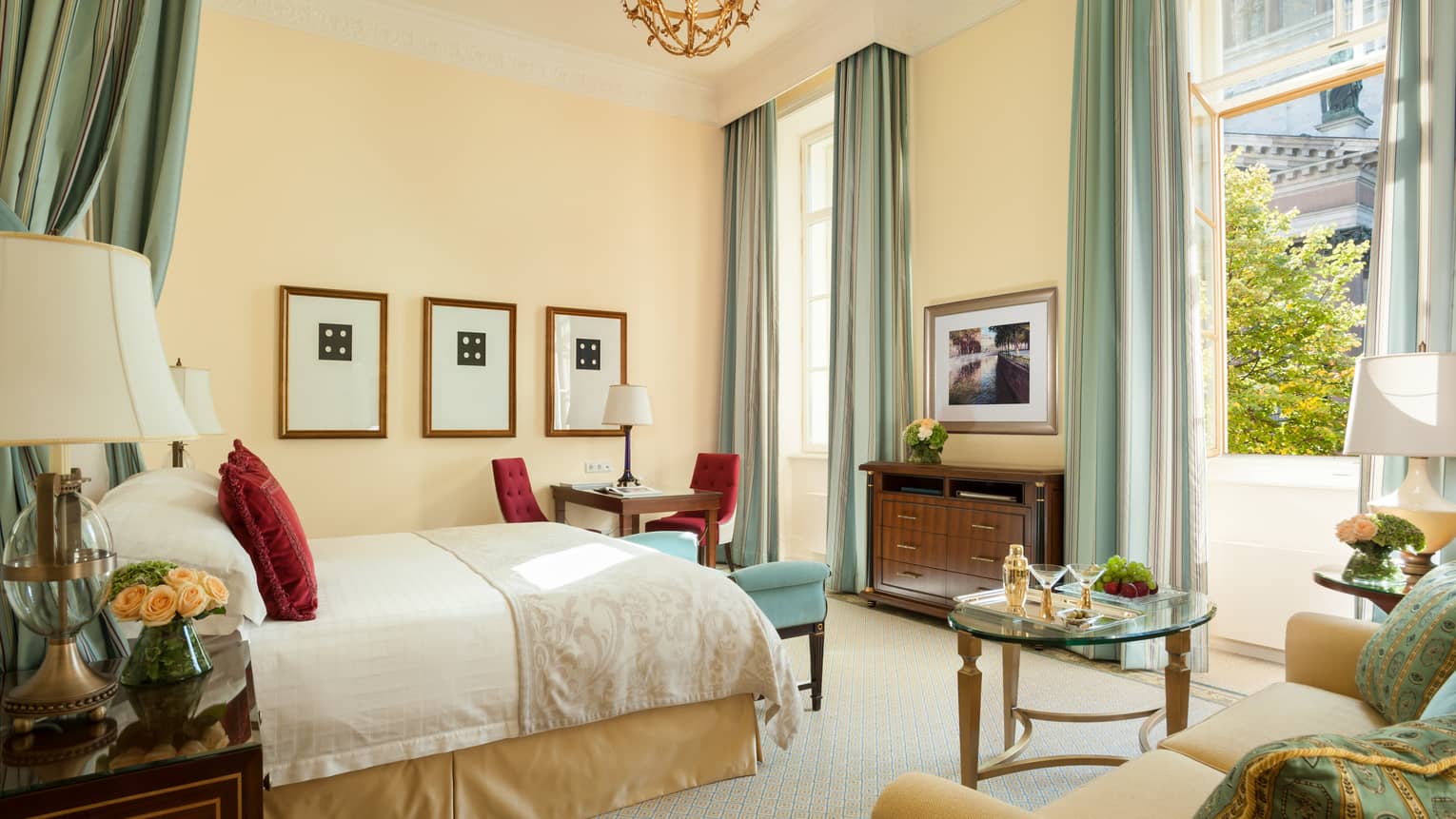 Four Seasons room with bed, loveseat, desk under high ceiling, pale blue and gold decor