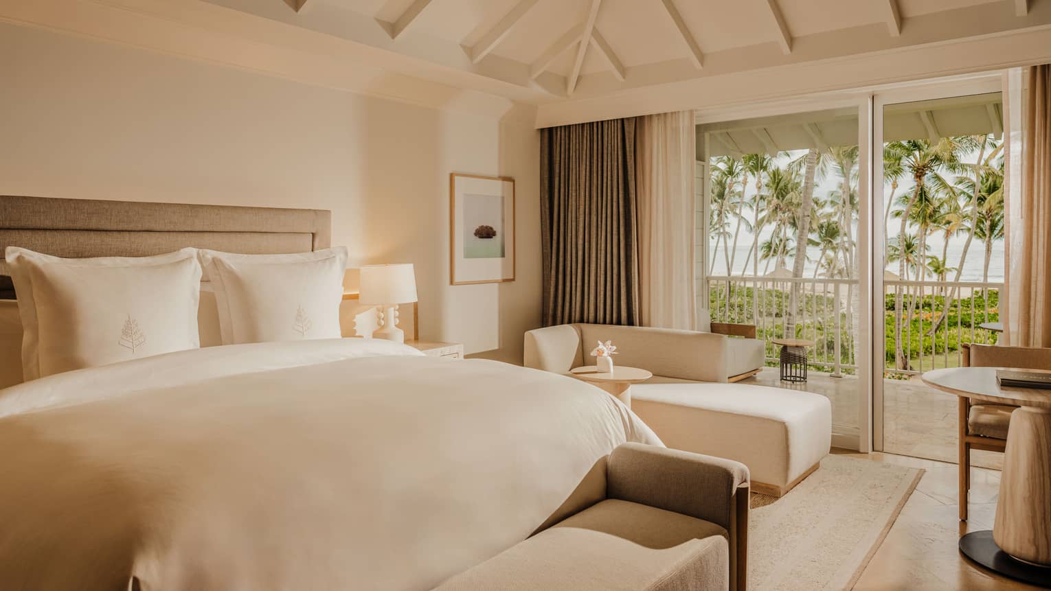 Luxury resort guest room with a plush king bed, chaise and balcony