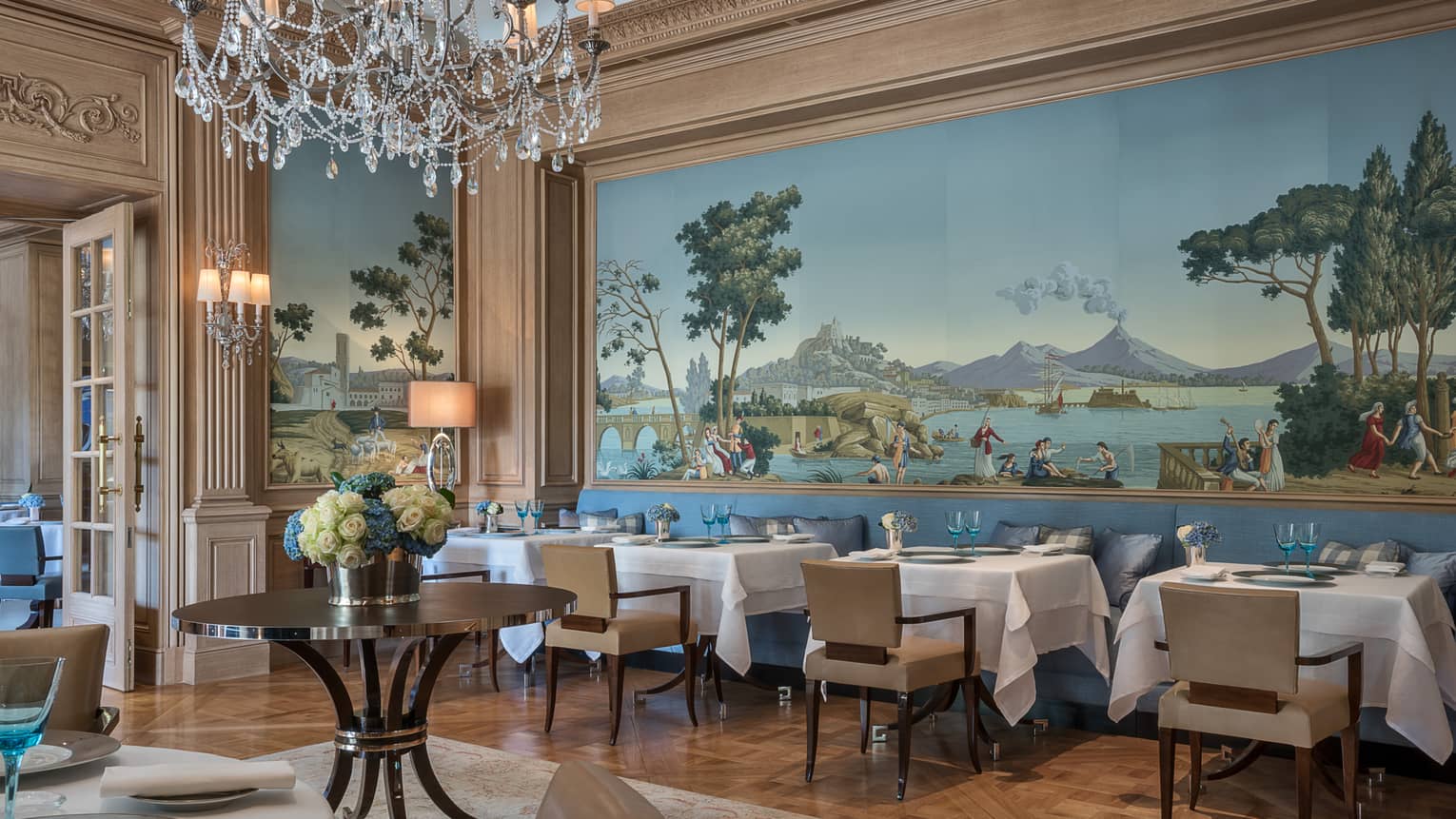 Il Lago elegant Northern Italian dining room with wall-sized mural above tables, chairs, crystal chandelier
