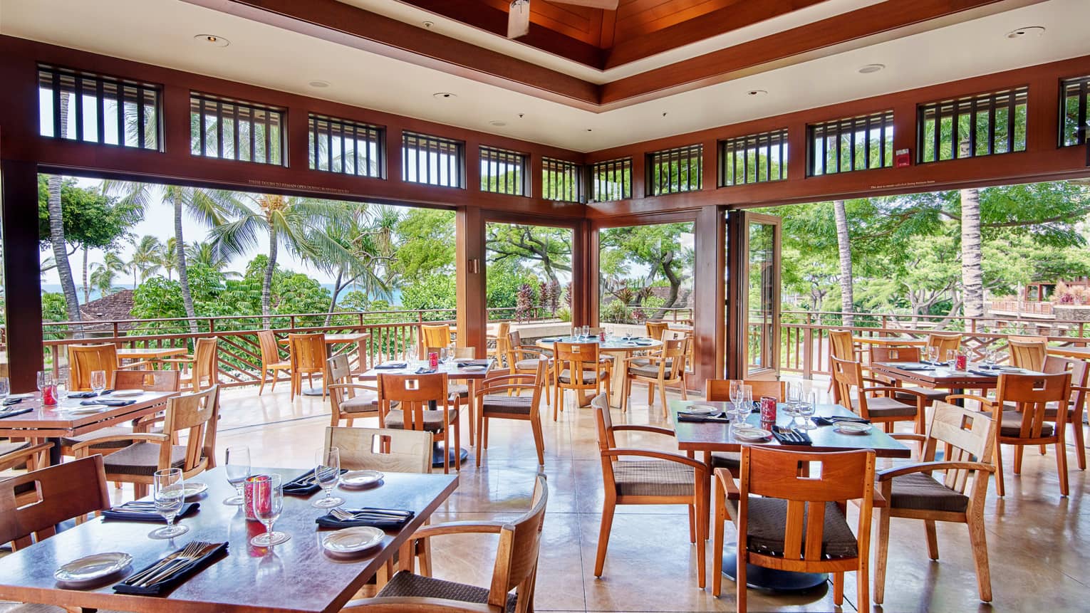 Hualalai Grille open-air dining room under tall wood ceilings 