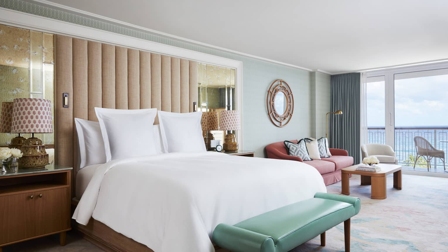 Ocean View Studio Suite bed and teal leather bench by seating area, balcony door