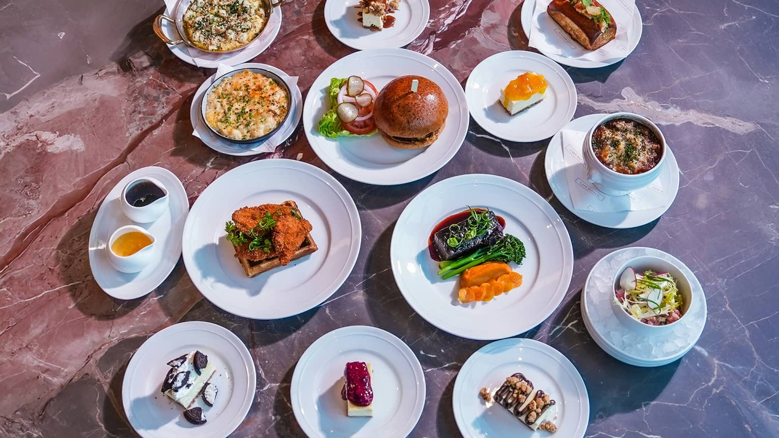 14 plates of brunch dishes all served on white plates on top of a grey marble table top