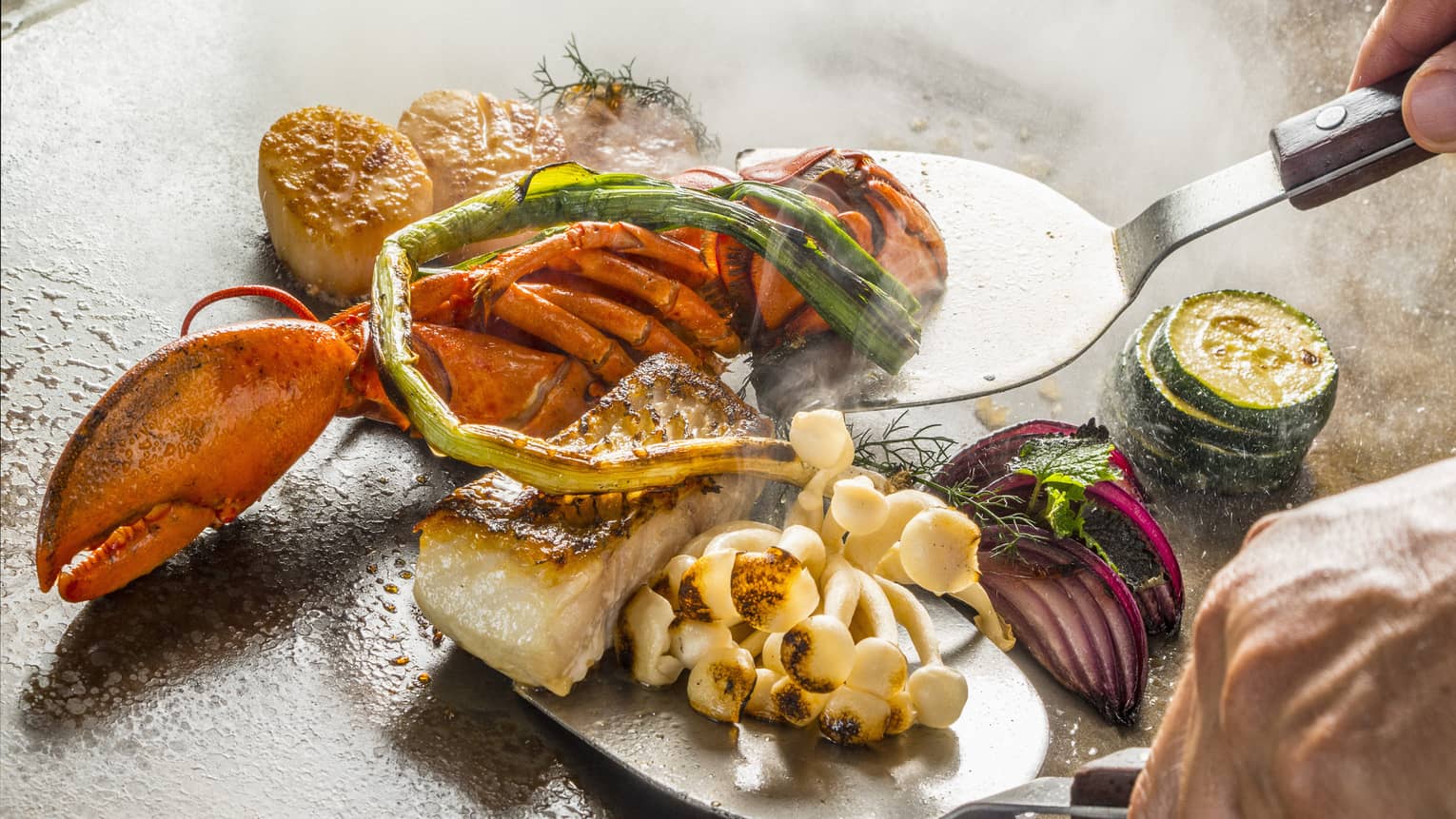 A chef cooks up some teppanyaki on a hot plate
