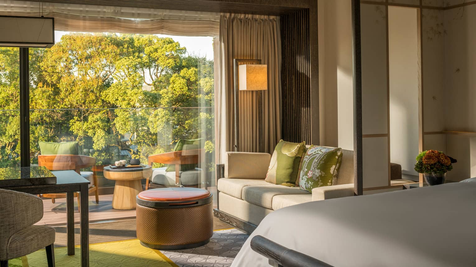 Four Seasons Room corner of bed by loveseat, round ottoman, desk by wide glass balcony door