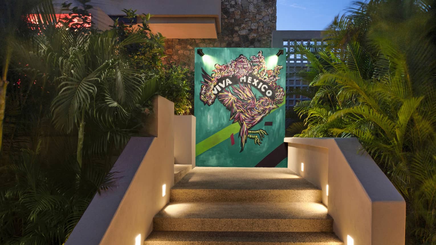 Stairs leading to wall art of a bird outside surrounded by plants.