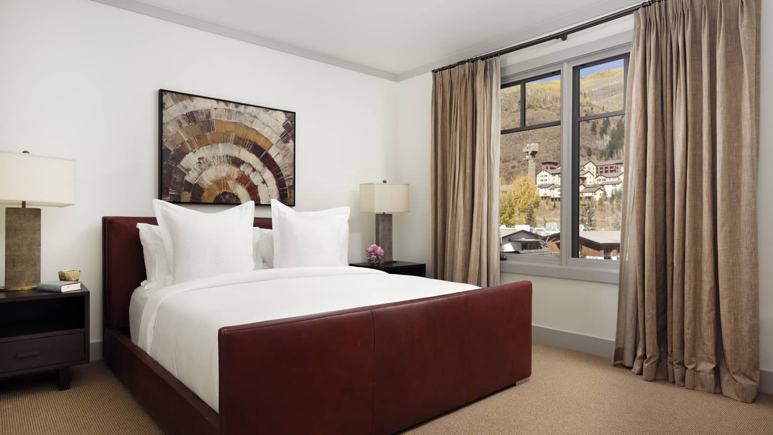 A private Vail residence is decorated with a dark wooden king bed and white linens 