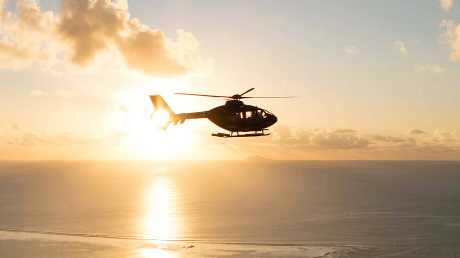 Helicopter over the sea at sunset