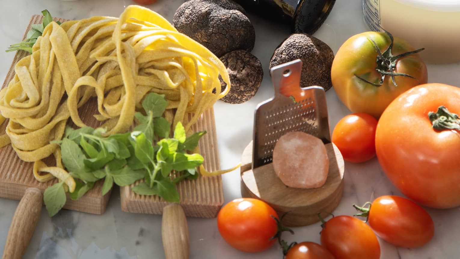 Array of Italian ingredients used in the Discover Regional menu each month (fresh fettuccine, tomatoes, burrata, olives, truffle)