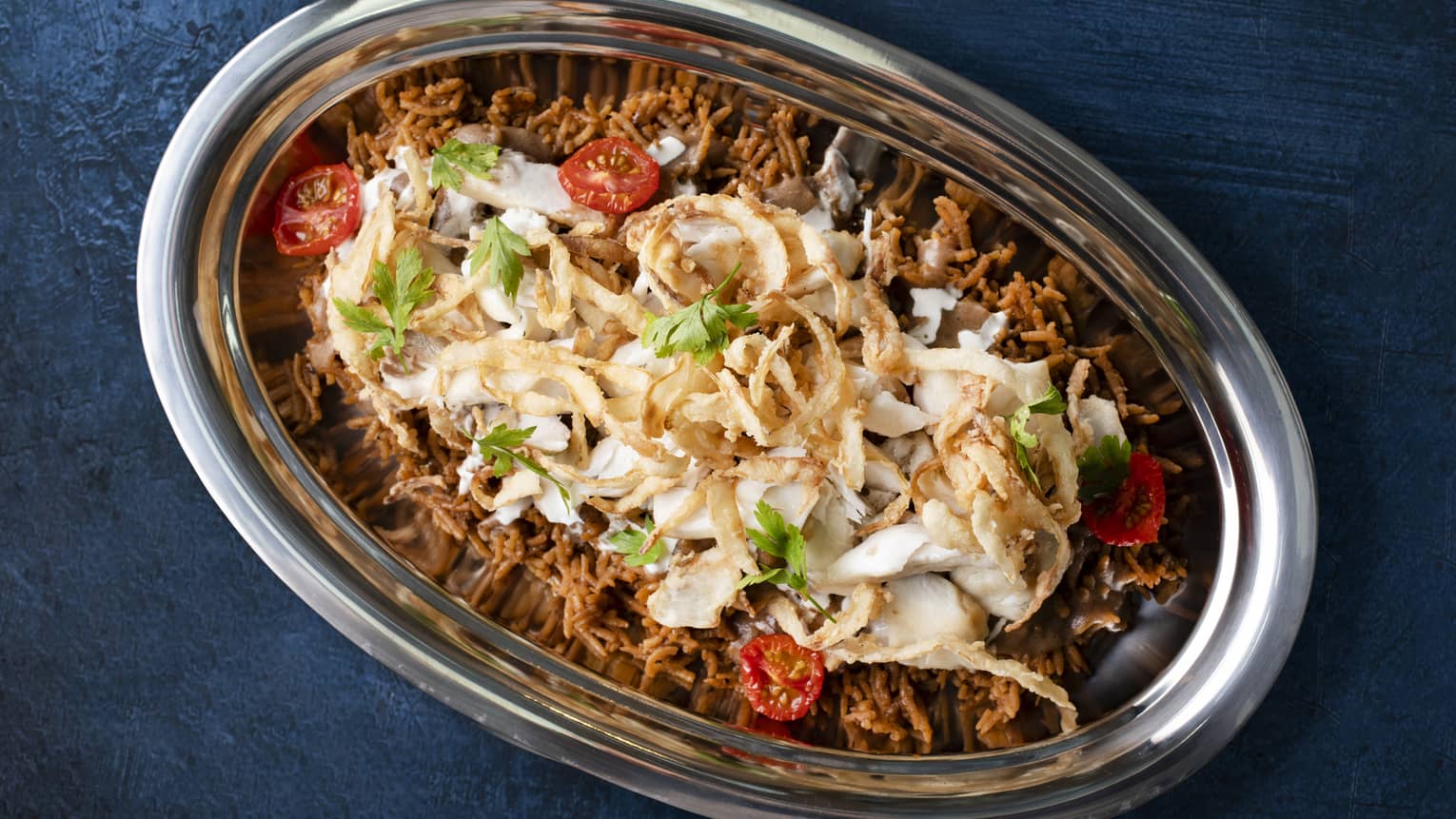 Grilled sea bass fillet served with caramelized onion rice, pine nuts, sun-dried tomatoes, tahini and spiced gravy sauce