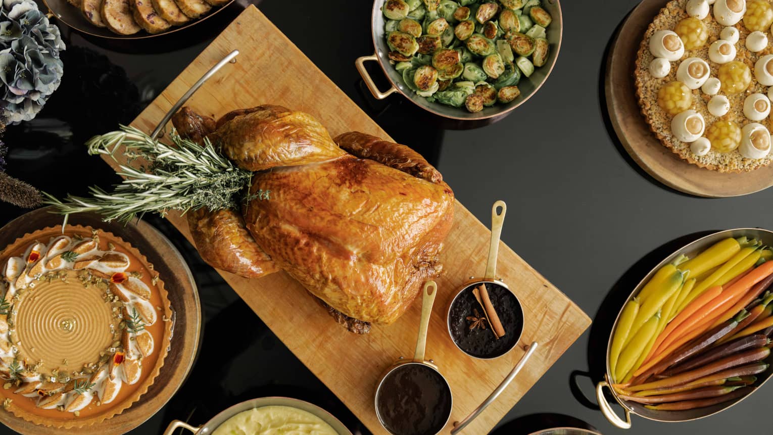 Table set with a roasted turkey, Brussels sprouts, sliced carrots and various other dishes for a holiday meal,Table set with a roasted turkey, Brussels sprouts, clived carrots and various other dishes for a holiday meal