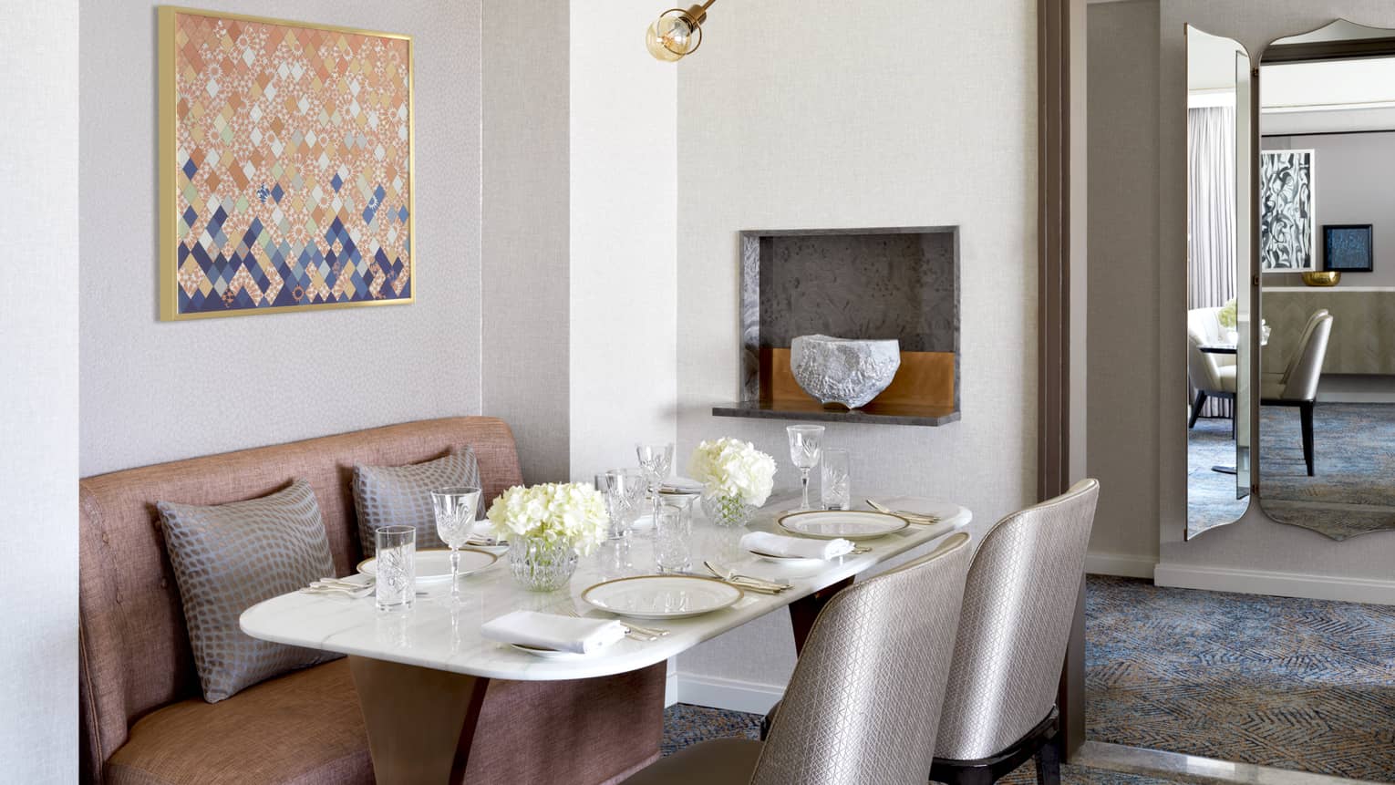 Dining table for four, with two silver chairs and a pink sofa